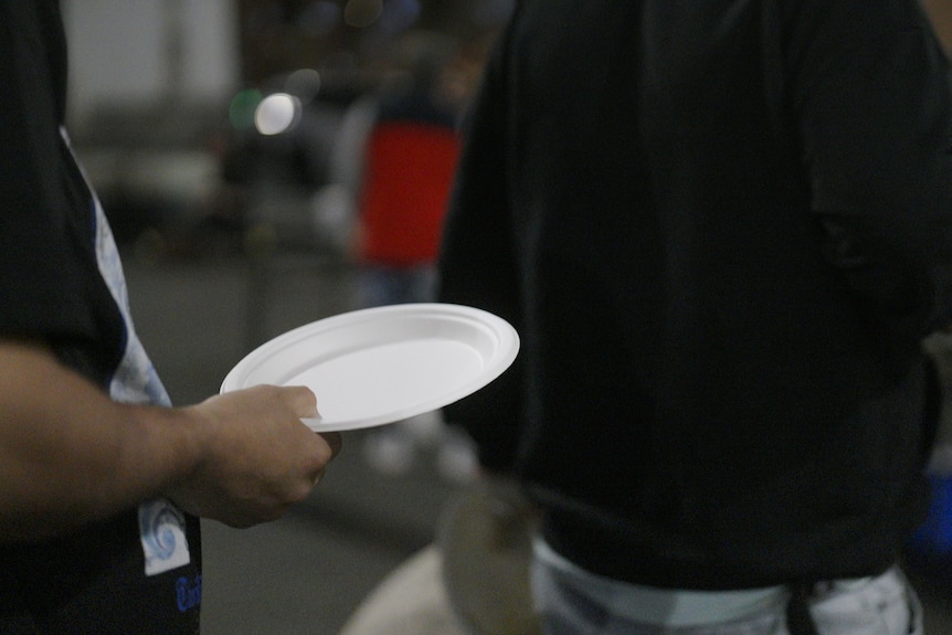 A man holding a plate in a queue.
