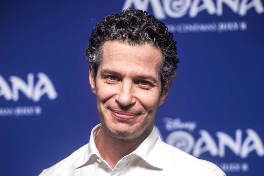 Thomas Kail smiling at the camera wearing a white shirt