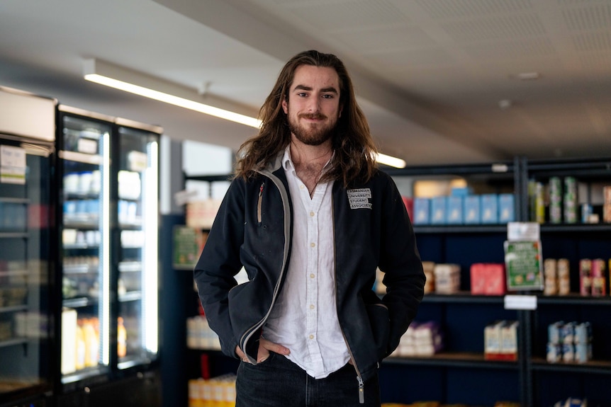 A man smiles for a photo in a mini grocery store