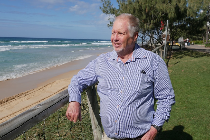 A man standing on a beach foreshore.