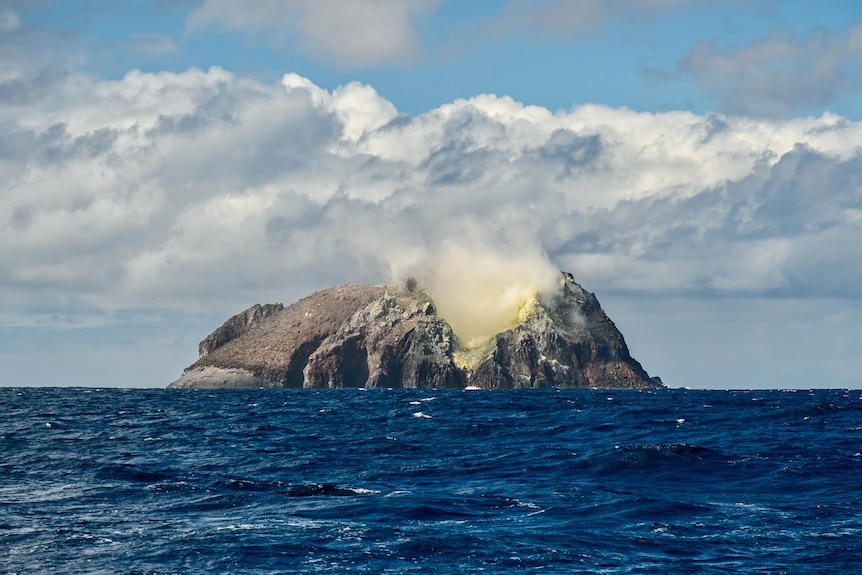 A volcanic island emits Sulphur in the Pacific Ocean.