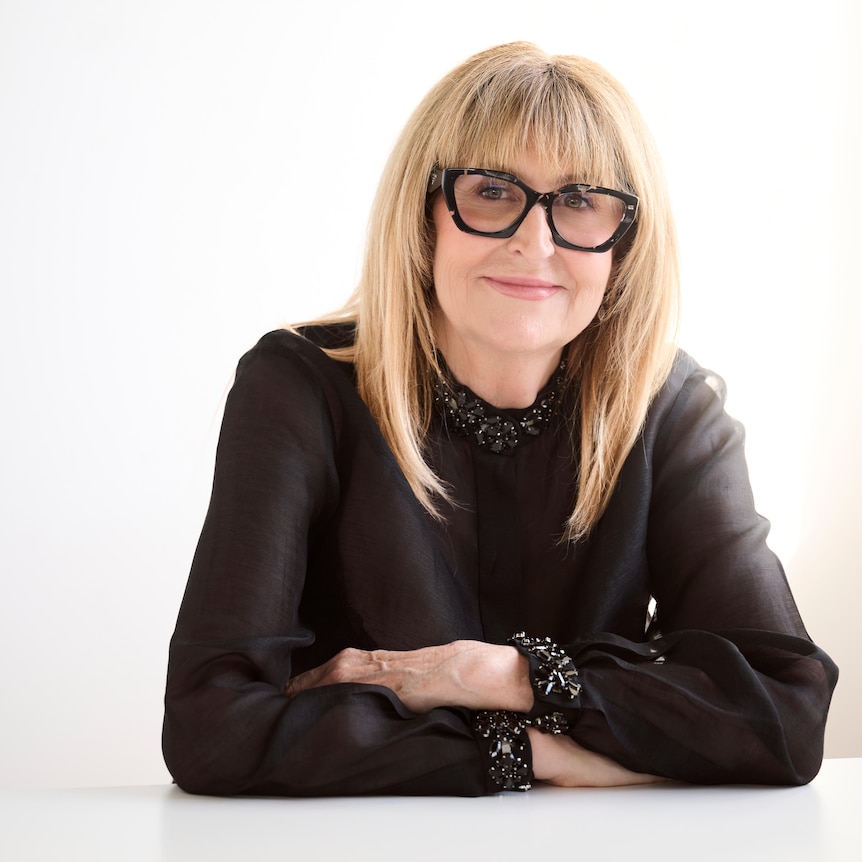 A woman, wearing glasses and a black top.