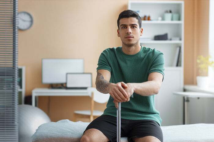 A young male patient sits with a cane, reflecting on things that happened with patients.