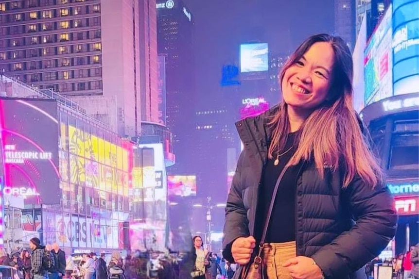 Czarina Gatbonton Tumaliuan smiles at the camera while standing in a city at night.