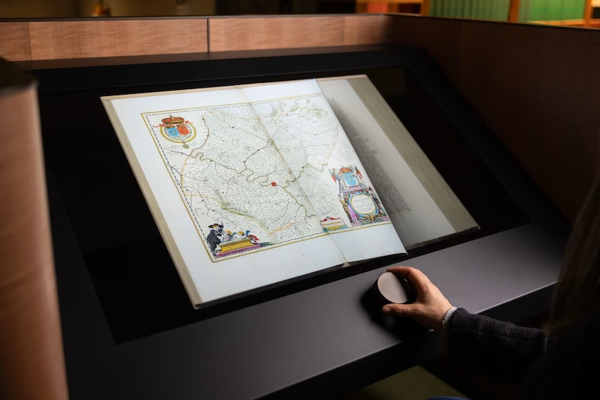 Book on display with hand reaching for a dial device.