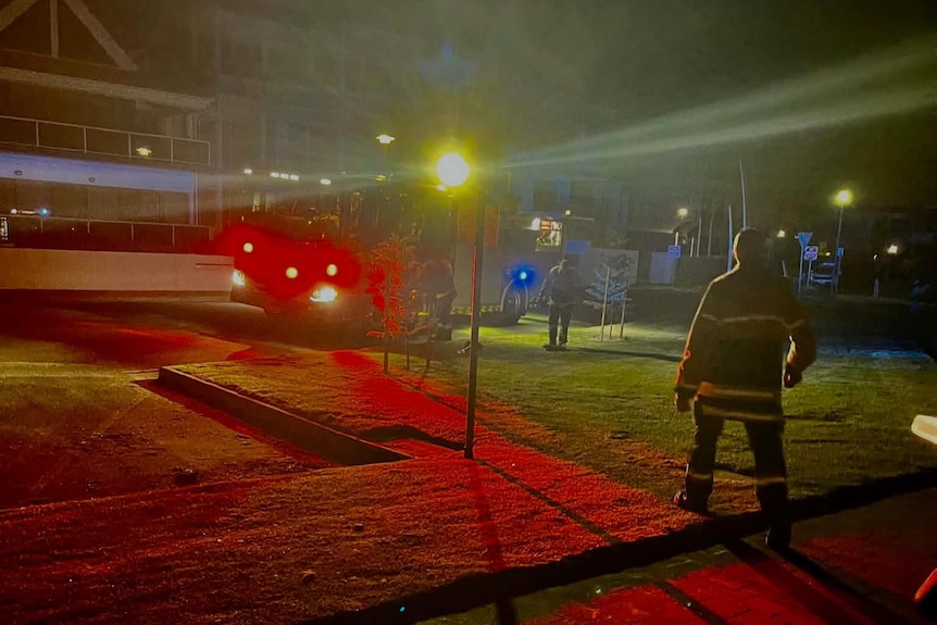 a firefighter walks towards a truck parked on the street next to a patch of grass
