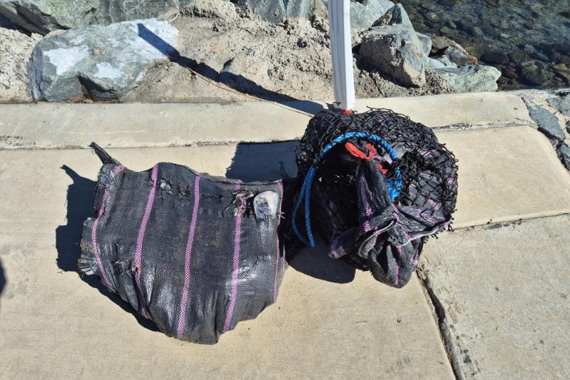 Two large black packages resting on a cement boat ramp.
