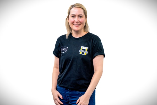 a woman standing in front of a white background.