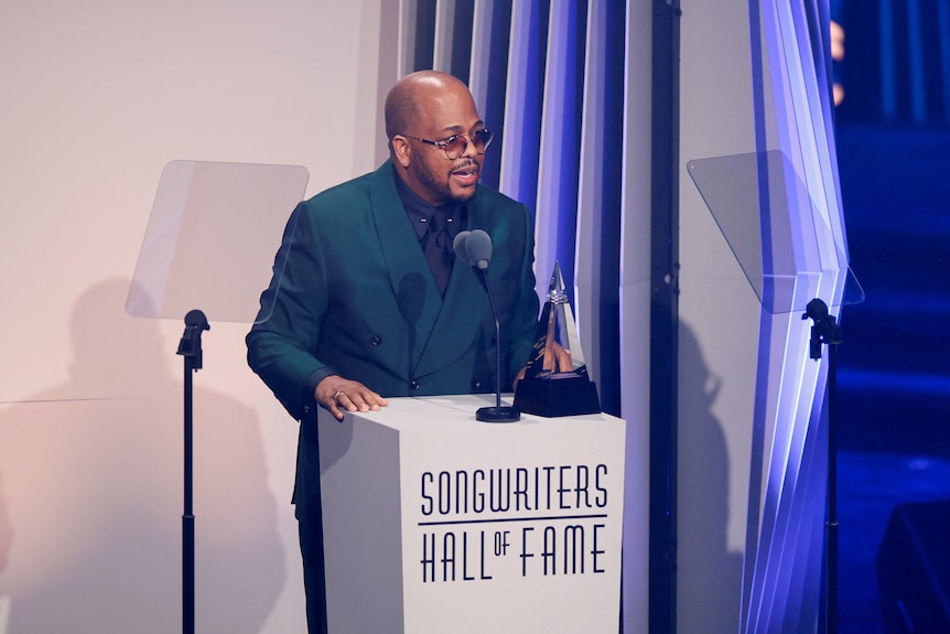 Christopher Tricky Stewart standing at a lectern with an award talking in a microphone