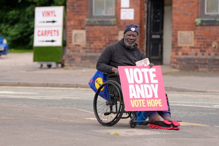 A man sitting in a wheelchair, holding a sign that says Vote Andy For Hope on it.