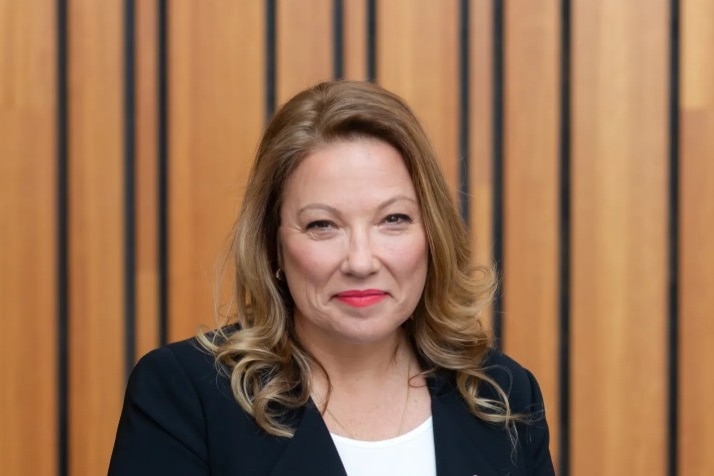 A woman with mid-length hair smiles at camera.