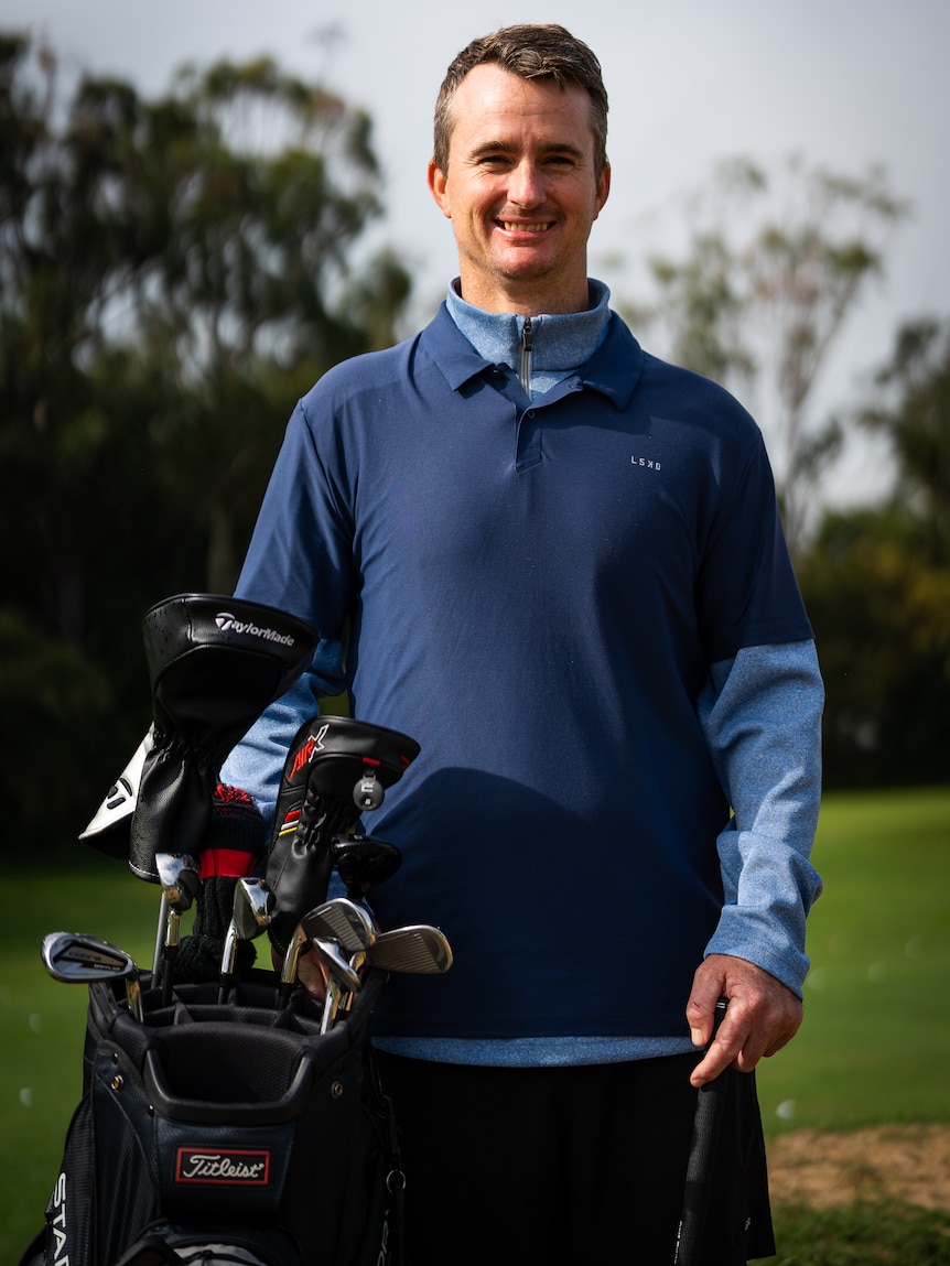 Chris Perry standing with his golf bag and clubs