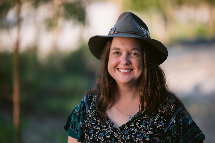 headshot of middle aged woman wearing wide brim hat