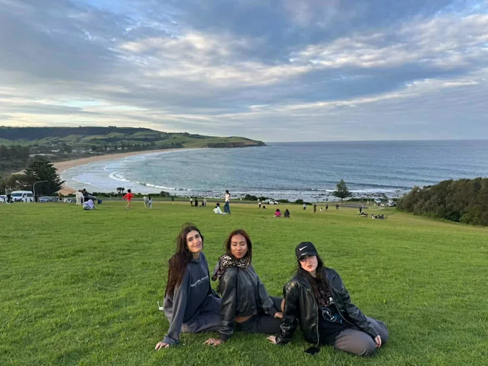 Three women pose on the reserve next to Tasman Drive.