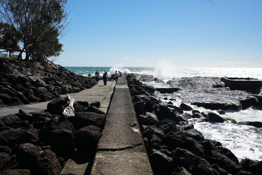 people walking along ocean breakwall