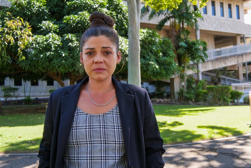 A woman stands, crying, outside a court building.