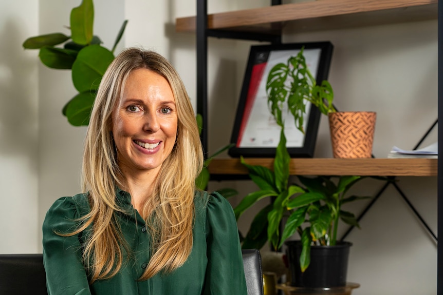 a woman with blonde hair and a green blouse in an office
