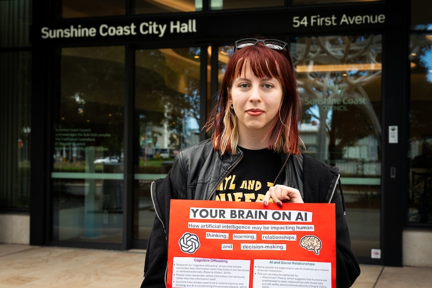 Student standing with a placard in front of Sunshine Coast Council building