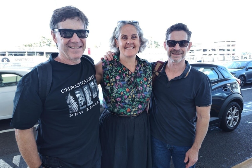 A picture of two men and one woman together, smiling.