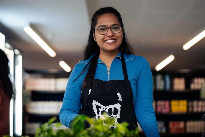 A woman smiles for a photo in a mini grocery store