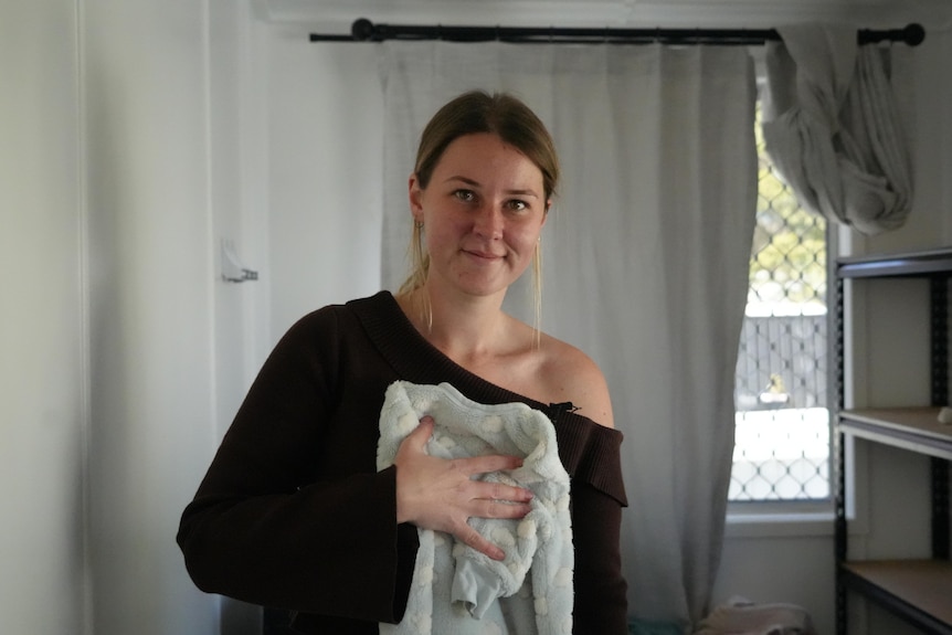 danica slack folding a onesie and smiling at the camera.