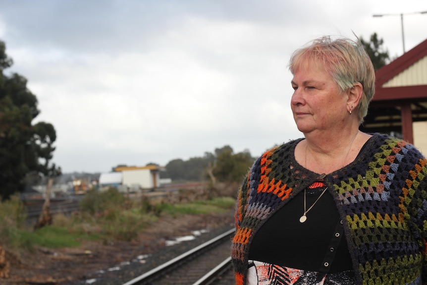 A side view of Jenny as she looks out onto train tracks
