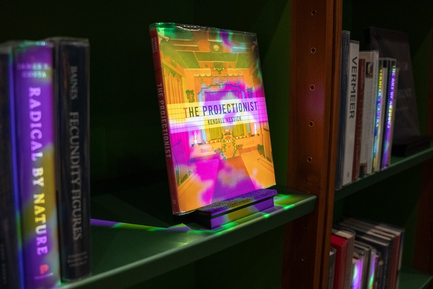 The shelves of a library, with some books lit up in neon colours.