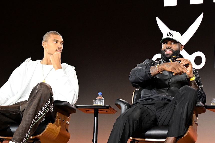 Victor Wembanyama looks at a speaking LeBron James