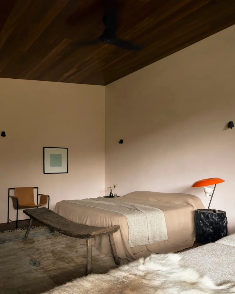 The main bedroom is modern with minimalist design, neutral colour palette with a pop of colour in orange lamp