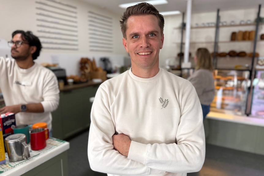 Man wearing a white jumper inside a bakery.