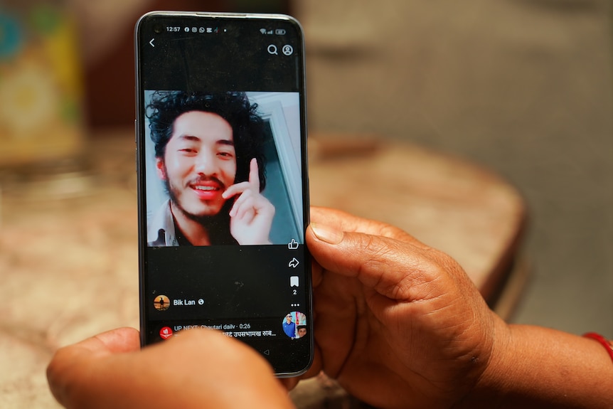 A photo of a smiling man is seen on the screen of a phone.