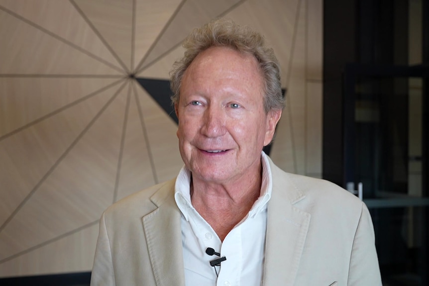A man in a beige suit speaks to a camera