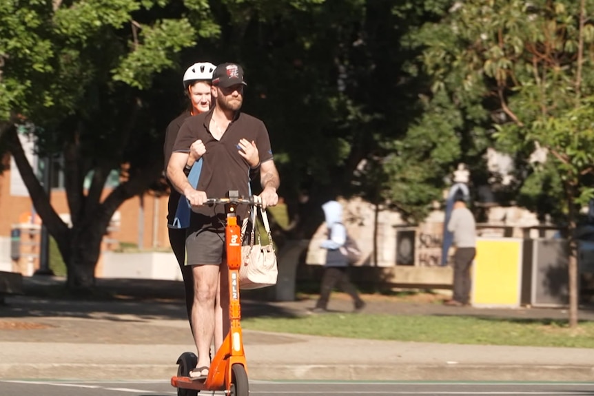 Two people on an e-scooter.