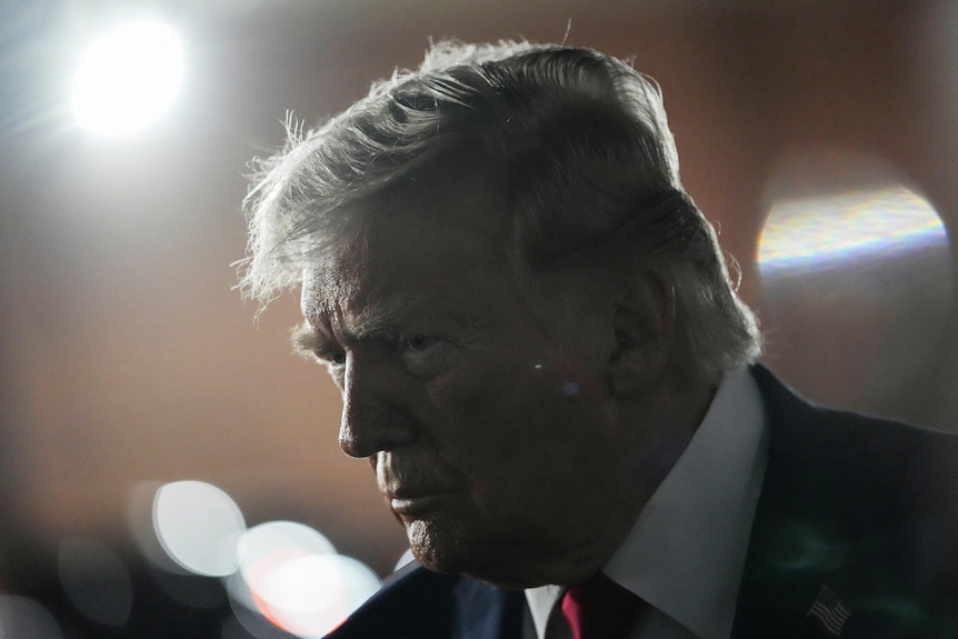 A man in a suit talks to the media.