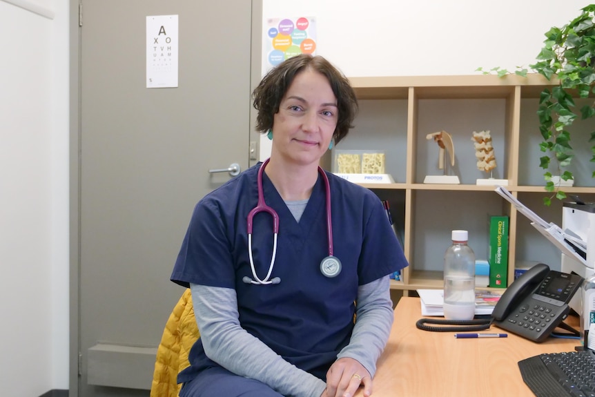 A doctor sitting at a desk with a stethoscope around her neck