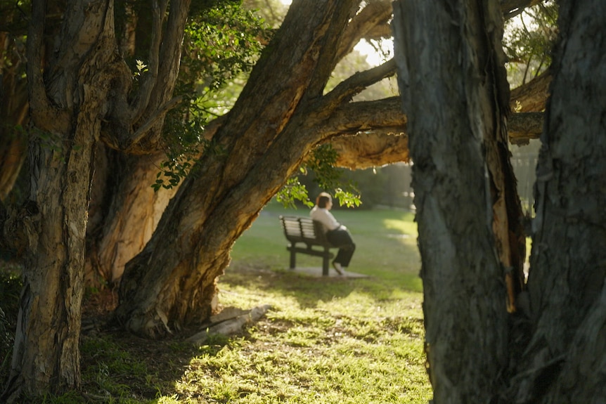 A woman sitting outside on a park bench.