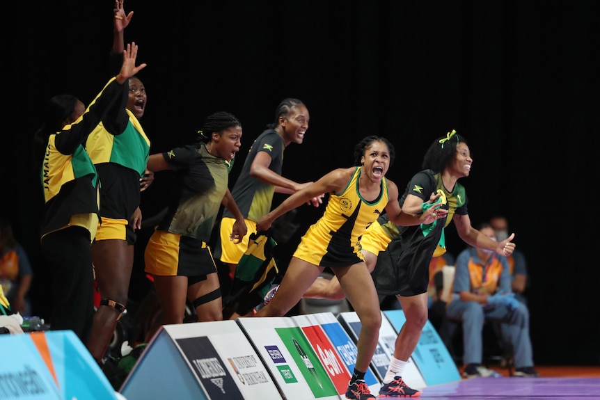 Women in black and yellow Jamaican netball uniform celebrating.
