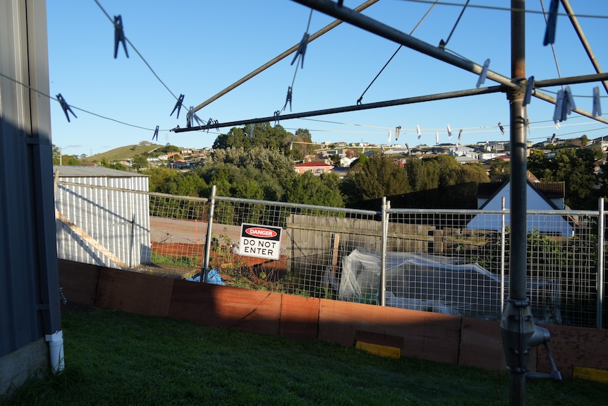 A construction site shows steep excavation close to a neighbouring property fence.