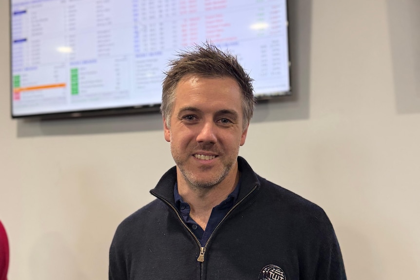 A man smiling in front of a trading screen