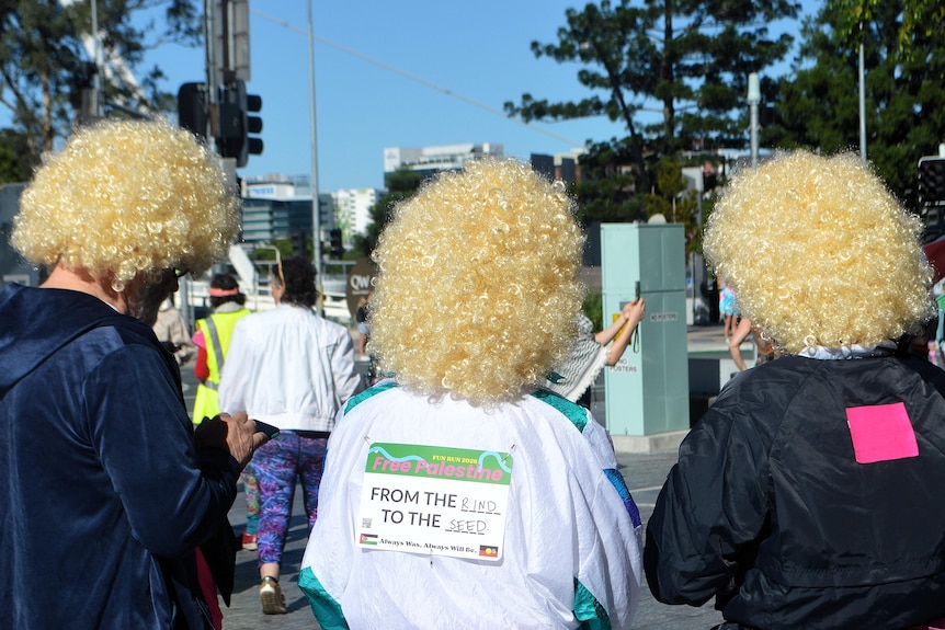 Three people in blonde curly wigs facing against the camera.