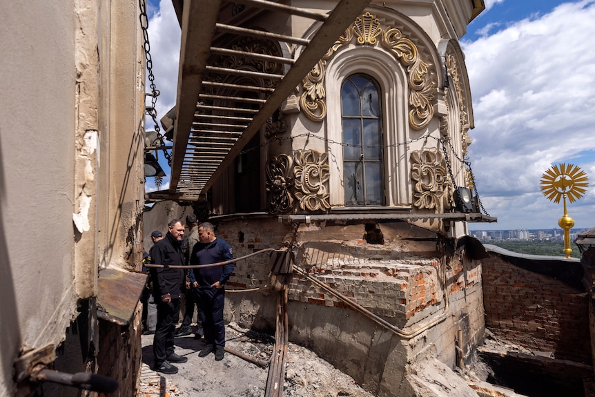 people inspect the damage to the roof of the Dormition Cathedral in Kyiv