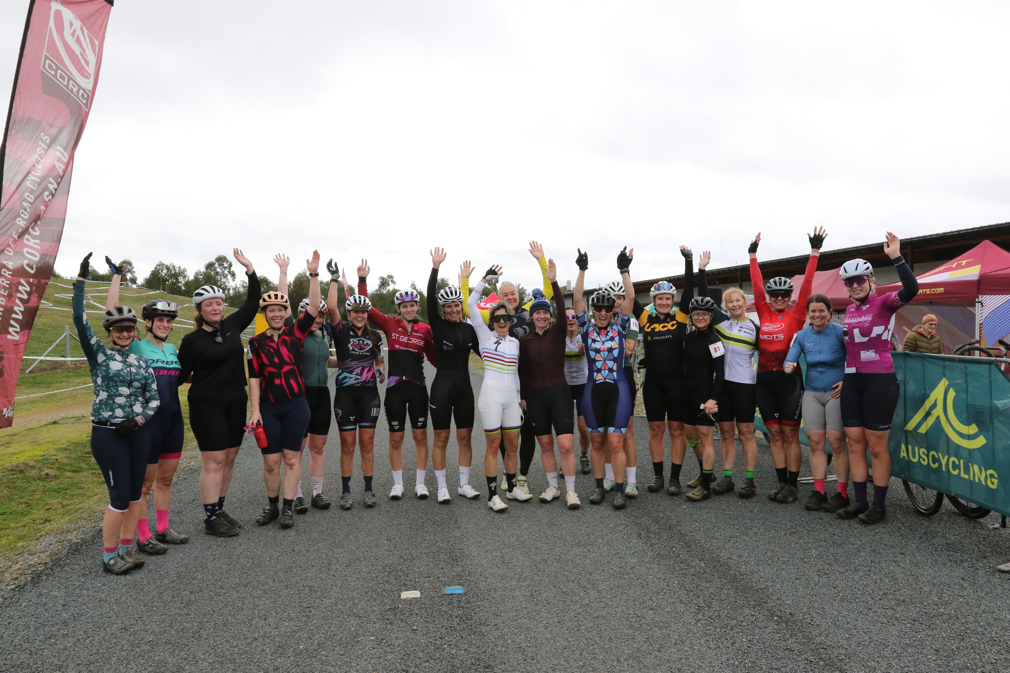 Riders in the women's categories in the AusCycling Cyclo-cross National Series round 4 in Canberra pose for a group photo with arms raised.