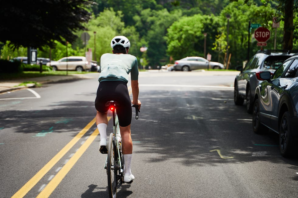 Cyclist riding along a tree-lined street under a clear sky. Cyclist riding along a tree-lined street under a clear sky.