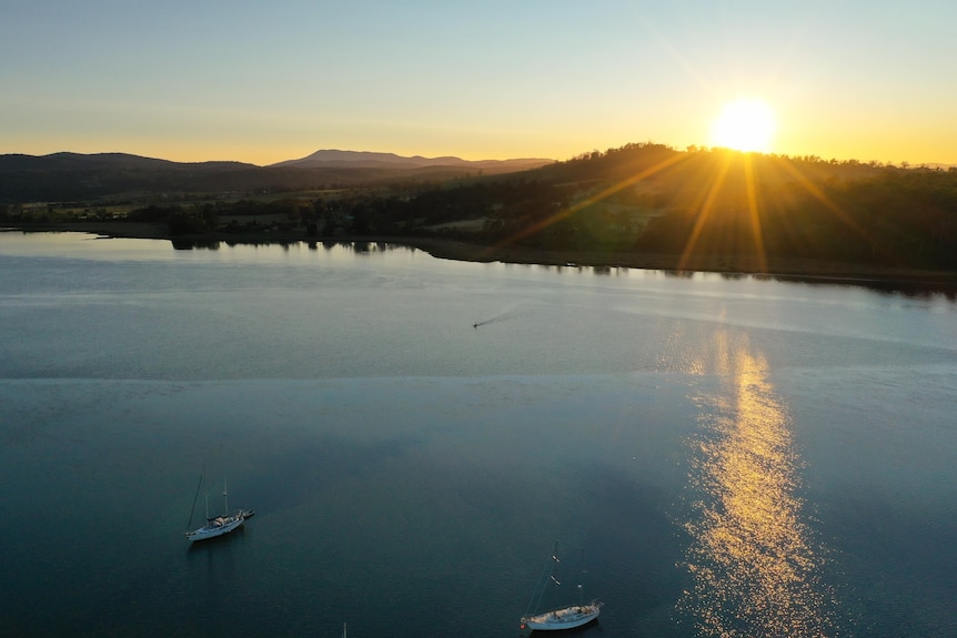 An aerial picture of a river with the sun low in the sky above.