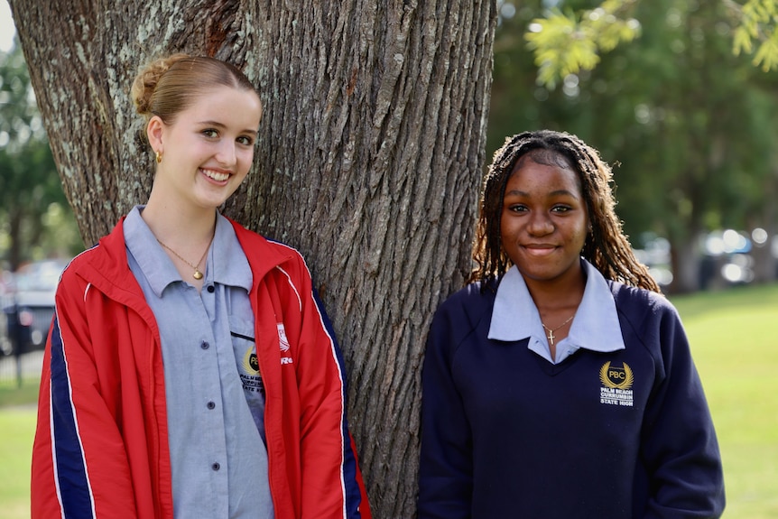 Two schoolgirls in front of a tree