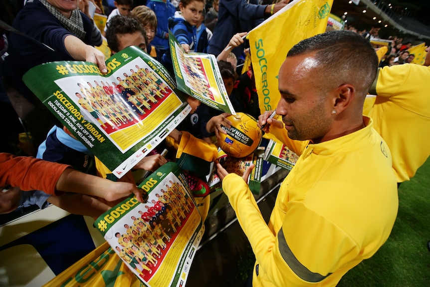 Archie Thompson signs autographs while playing for the Socceroos