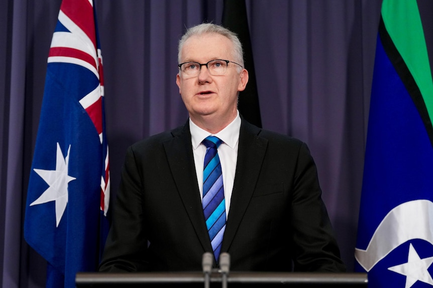 a male politician wearing a suit speaking at a lectern