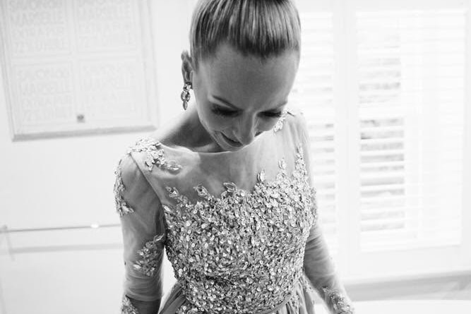 A black and white photo of a woman looking down wearing a sequined dress.