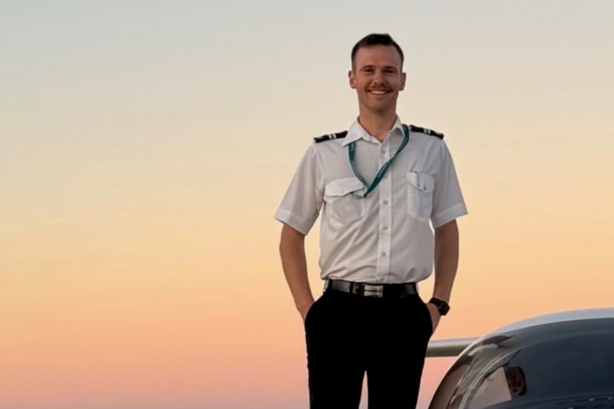 A pilot stands on a plane wing.