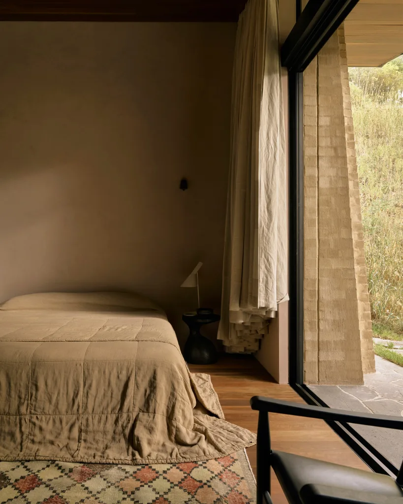 A minimalist bedroom in a brutalist house with a pattern rug.